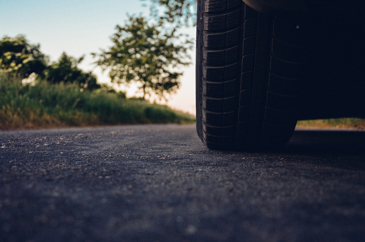 A car's tire on a road near a tree