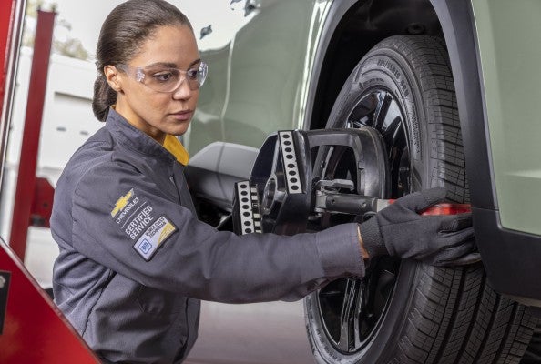 Female Chevy technician checking the tires on a Chevrolet car